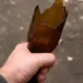 Mano che stringe una bottiglia di vetro rotta, usata come arma in un'aggressione