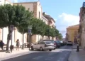 Via del centro di Santa Croce Camerina con auto parcheggiate e passanti in una giornata di sole