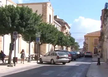 Via del centro di Santa Croce Camerina con auto parcheggiate e passanti in una giornata di sole