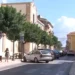 Via del centro di Santa Croce Camerina con auto parcheggiate e passanti in una giornata di sole