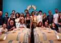 Il team di Casa Grazia posa tra le botti della cantina, sotto il logo aziendale, per la presentazione di Aischylia