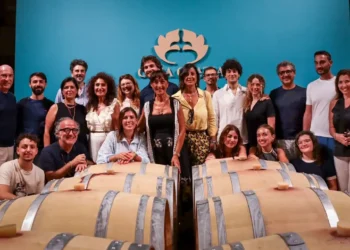 Il team di Casa Grazia posa tra le botti della cantina, sotto il logo aziendale, per la presentazione di Aischylia