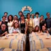 Il team di Casa Grazia posa tra le botti della cantina, sotto il logo aziendale, per la presentazione di Aischylia