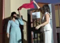 Lorena e Giusy tagliano un nastro rosso davanti all'ingresso decorato con il logo a forma di albero colorato