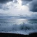 Nuvoloni scuri e mare mosso, con onde che si infrangono sulla spiaggia di ciottoli durante una fase di maltempo
