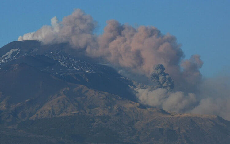 Nube di cenere si leva dal cratere sommitale dell'Etna, cielo sereno sullo sfondo
