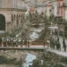 Modica dopo l'alluvione del 1902: alveo pieno di detriti tra i palazzi, gente su una passerella di legno e sulle strade
