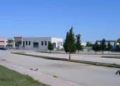 Piazzale di una zona artigianale con capannoni, auto parcheggiate