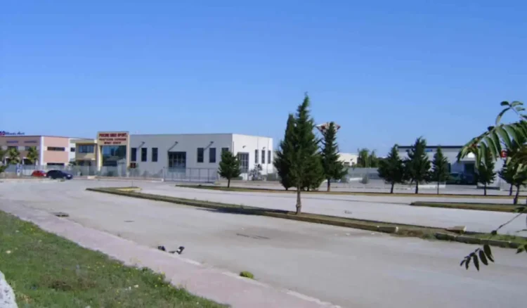 Piazzale di una zona artigianale con capannoni, auto parcheggiate