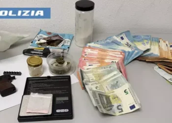 Denaro contante e materiale sequestrato dalla polizia, con una parte di un'arma visibile sul lato sinistro
