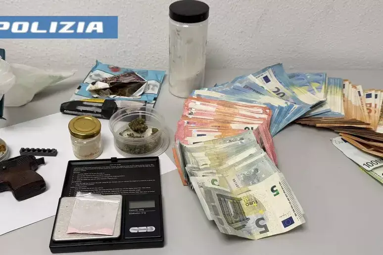 Denaro contante e materiale sequestrato dalla polizia, con una parte di un'arma visibile sul lato sinistro