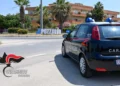 Auto dei carabinieri parcheggiata vicino alla rotatoria con la scritta Pozzallo, tra palme e palazzine