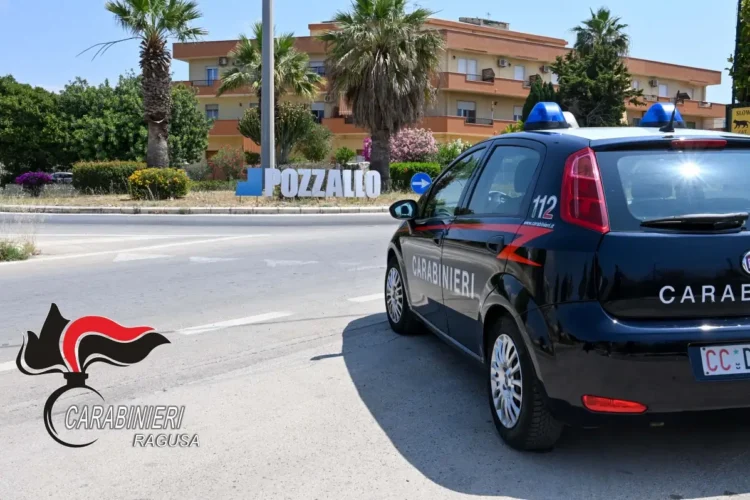 Auto dei carabinieri parcheggiata vicino alla rotatoria con la scritta Pozzallo, tra palme e palazzine