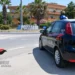 Auto dei carabinieri parcheggiata vicino alla rotatoria con la scritta Pozzallo, tra palme e palazzine