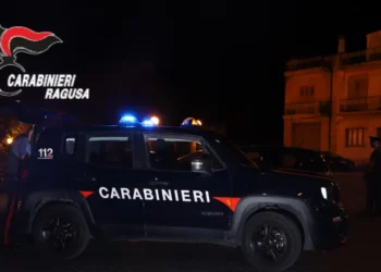 Auto dei Carabinieri con lampeggianti accesi e militari in servizio nella notte davanti a un edificio storico illuminato