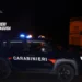 Auto dei Carabinieri con lampeggianti accesi e militari in servizio nella notte davanti a un edificio storico illuminato