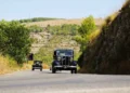 Due auto d'epoca, tra cui la vettura numero 61, in marcia su una strada di collina nella campagna iblea