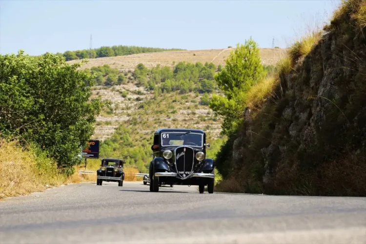 Due auto d'epoca, tra cui la vettura numero 61, in marcia su una strada di collina nella campagna iblea