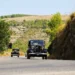 Due auto d'epoca, tra cui la vettura numero 61, in marcia su una strada di collina nella campagna iblea