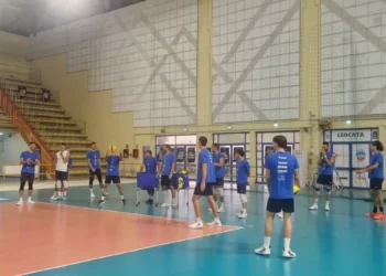 Giocatori dell'Avimec Modica in maglia blu durante un allenamento in palestra, uno palleggia al centro del campo