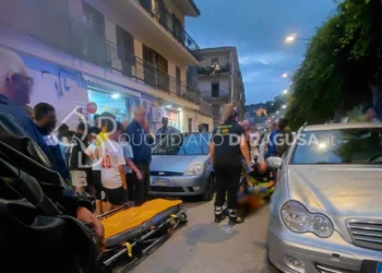 Soccorritori del 118 prestano aiuto al bambino investito a Modica, accanto a una Ford grigia, con una barella in strada