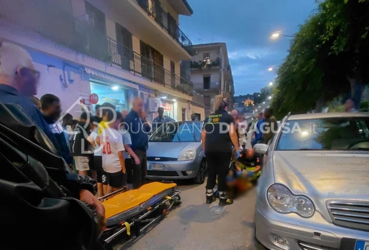 Soccorritori del 118 prestano aiuto al bambino investito a Modica, accanto a una Ford grigia, con una barella in strada