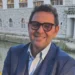 Ritratto di Gigi Bellassai, capogruppo del Pd, con occhiali e giacca blu accanto a un canale cittadino