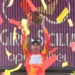 Brandon McNulty in maglia giallorossa di leader alza il trofeo sul podio del Giro di Sicilia tra coriandoli rossi e gialli