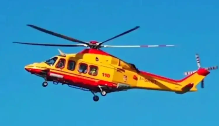 Elicottero del servizio di elisoccorso 118, giallo e rosso, in volo contro un cielo azzurro
