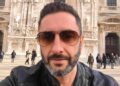 Uomo con barba brizzolata e occhiali da sole, ritratto all'aperto davanti a un edificio monumentale.