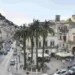 Vista di una via del centro storico di Modica con palme, tavolini all'aperto ed edifici storici