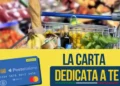 Carrello con pane, banane e basilico sopra la scritta La Carta Dedicata a Te e una carta prepagata di Poste Italiane