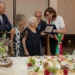 Centenaria di Modica Maria Cavallo riceve una targa dalla sindaca con fascia tricolore, davanti una torta a forma di 100