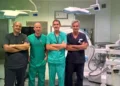Quattro medici in divisa da sala operatoria a braccia conserte, in una sala di chirurgia vascolare a Vittoria con arco a C