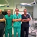 Quattro medici in divisa da sala operatoria a braccia conserte, in una sala di chirurgia vascolare a Vittoria con arco a C