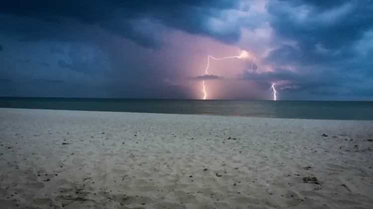 Temporale con fulmini sul mare, visto da una spiaggia al crepuscolo
