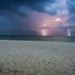 Temporale con fulmini sul mare, visto da una spiaggia al crepuscolo