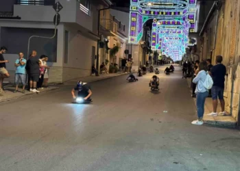 Un carramatto in discesa lungo una via illuminata di Giarratana, pubblico ai lati della strada durante la corsa notturna