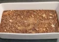 Pirofila bianca con cuddureddi nel mosto scuro, coperti da mandorle tostate tritate e da una spolverata di cannella