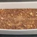 Pirofila bianca con cuddureddi nel mosto scuro, coperti da mandorle tostate tritate e da una spolverata di cannella
