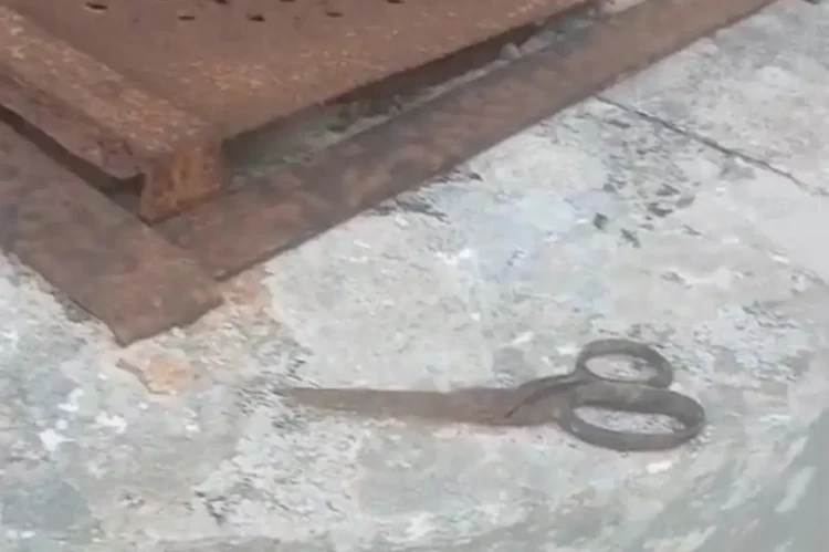 Forbice in ferro sul cemento accanto a una lamiera arrugginita nel serbatoio di Vittoria