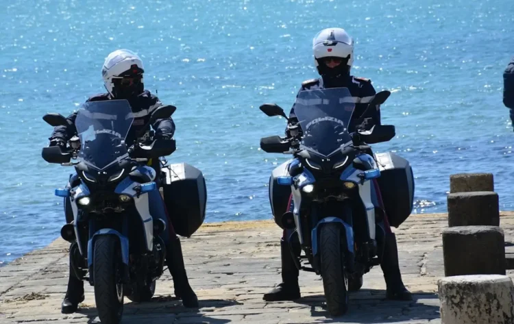 Agenti della Polizia di Stato pattugliano in moto una banchina vicino al mare