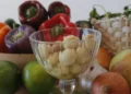 Peperoni colorati, cipolle, lime e una coppa di vetro con spicchi d'aglio sbucciati: ingredienti da dieta mediterranea