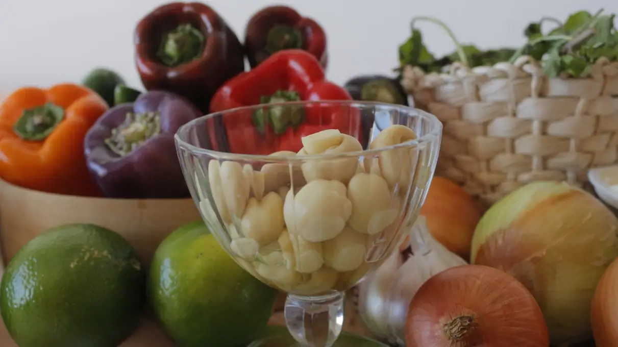 Peperoni colorati, cipolle, lime e una coppa di vetro con spicchi d'aglio sbucciati: ingredienti da dieta mediterranea
