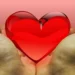 Due mani aperte reggono un cuore rosso lucido su sfondo rosa, simbolo della donazione degli organi