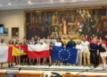 Giovani dello scambio Erasmus a Modica con le bandiere di Italia, Sicilia, Polonia e Unione Europea in una sala del Comune