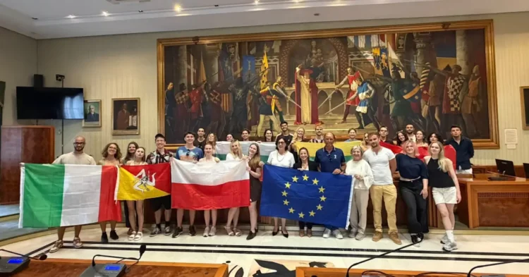Giovani dello scambio Erasmus a Modica con le bandiere di Italia, Sicilia, Polonia e Unione Europea in una sala del Comune