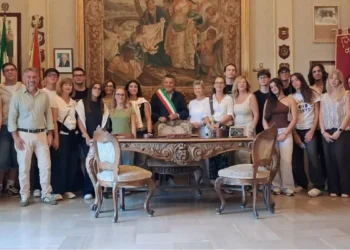 Il sindaco di Scicli con la fascia tricolore posa in Municipio con studenti e docenti, accanto a una scrivania d'epoca