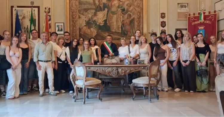 Il sindaco di Scicli con la fascia tricolore posa in Municipio con studenti e docenti, accanto a una scrivania d'epoca