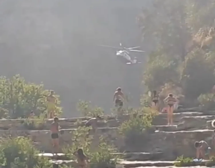 Elicottero dei vigili del fuoco sorvola i Laghetti di Cavagrande durante il soccorso, bagnanti sulle terrazze rocciose